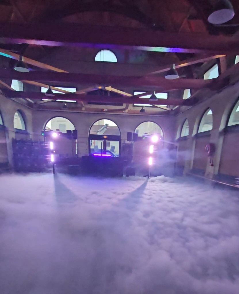 Salle voûtée recouverte de fumée lourde, set DJ et faisceaux violets