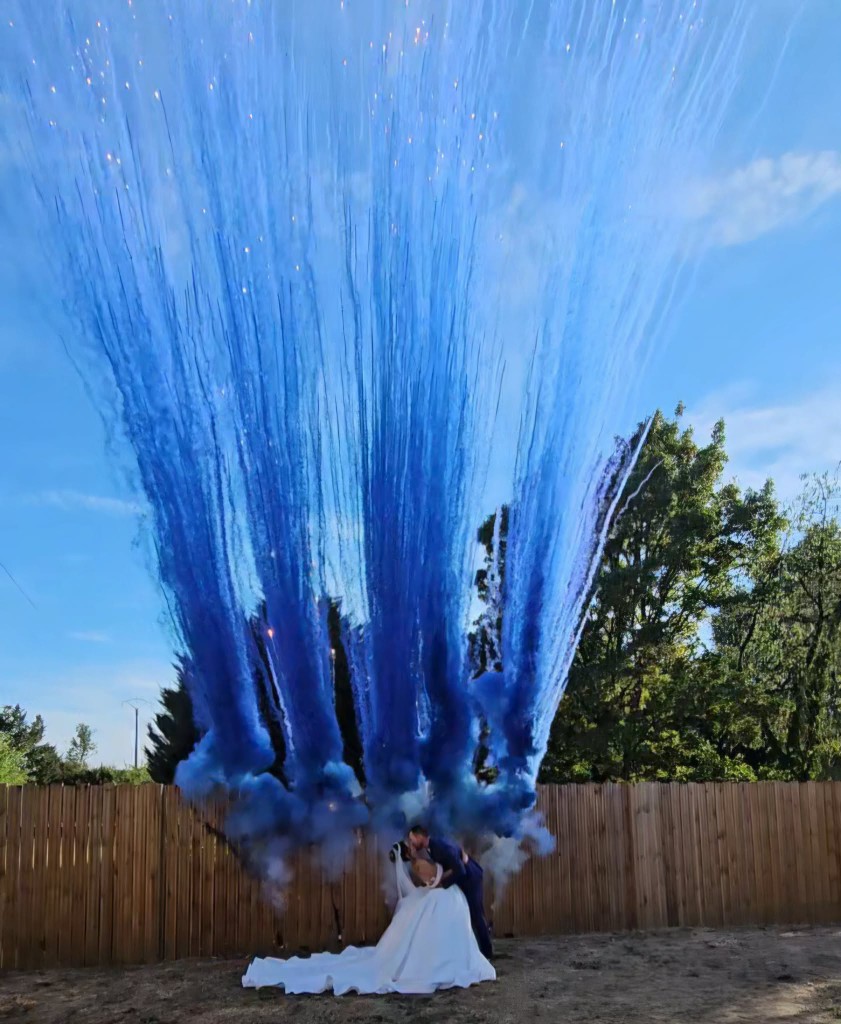 Les mariés sous un jet de poudre bleue en extérieur